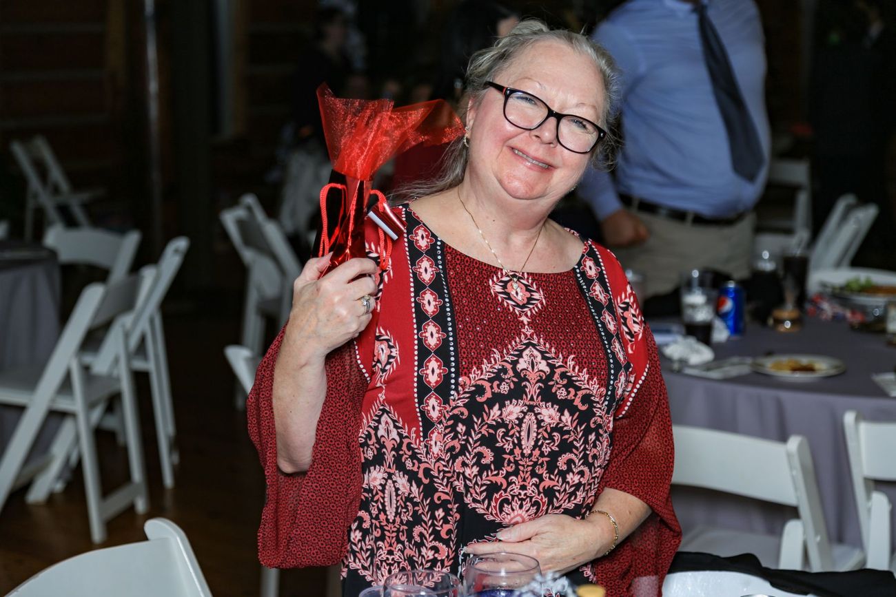 A smiling guest holding up a red gift bag