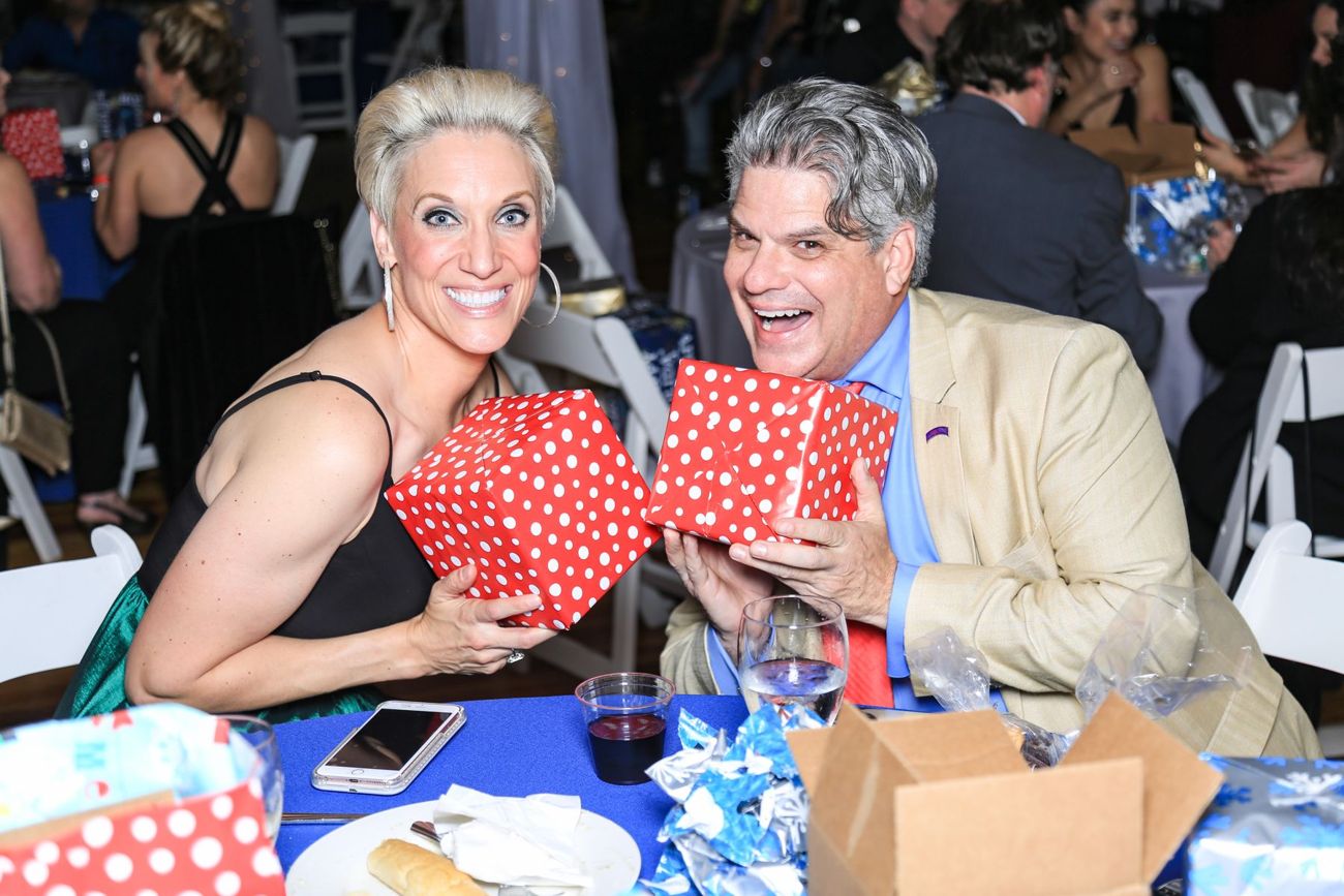 Two guests laughing and holding up red polka-dot gift boxes