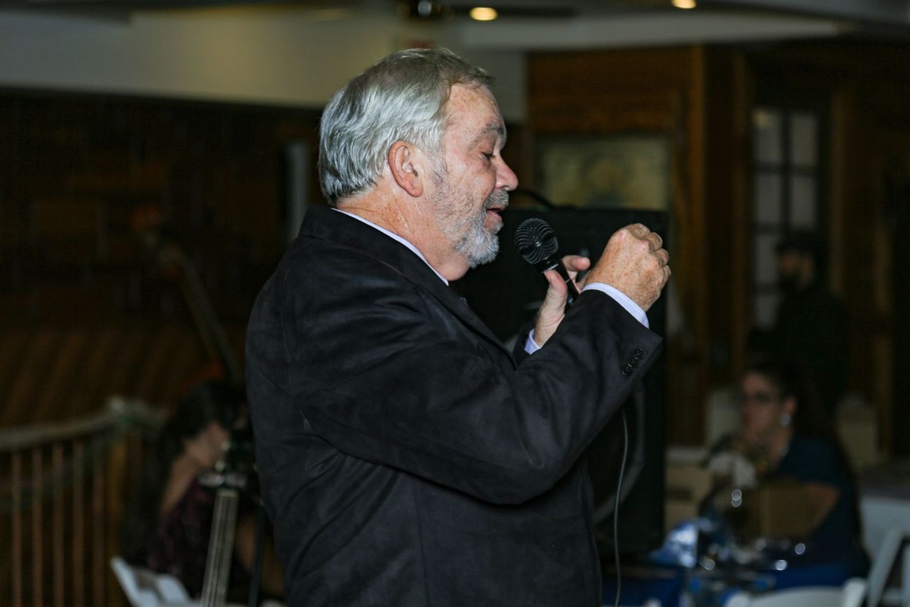 A gray-haired man singing into a microphone